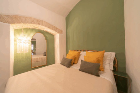 Altra camera da letto matrimoniale trullo Alfieri, con specchiera, sgabello, comò, finestra a muro, specchio, climatizzatore e termosifone.