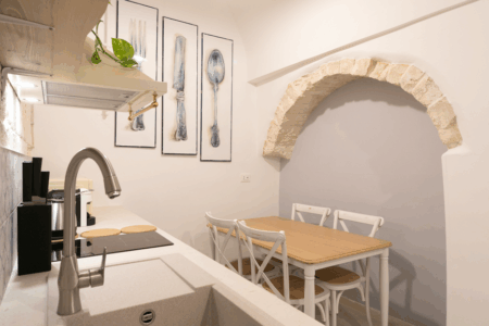 Cucina abitabile trullo Alfieri con diversi accessori: piano cottura ad induzione, lavabo, bollitore, macchina per il caffe, tavoli e sedie.