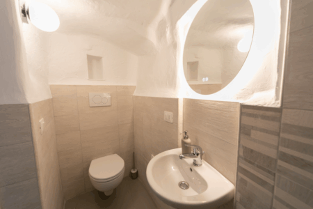 Altro bagno del trullo Alfieri con lavandino, bidet, doccia a muro con tendina. Ambiente dai toni neutri e rilassanti.