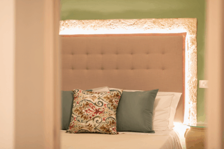 Camera da letto matrimoniale trullo Alfieri, con specchiera, sgabello, comò, finestra a muro, specchio, climatizzatore e termosifone.