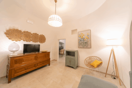 Salotto trullo Alfieri con smart tv, mobiletto da tv, divano, poltroncina, angolo con caminetto tavoli e sedie.