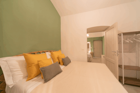 Altra camera da letto matrimoniale trullo Alfieri, con specchiera, sgabello, comò, finestra a muro, specchio, climatizzatore e termosifone.